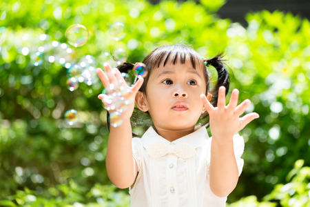 Lovely girl want to catch with the bubbleの写真素材