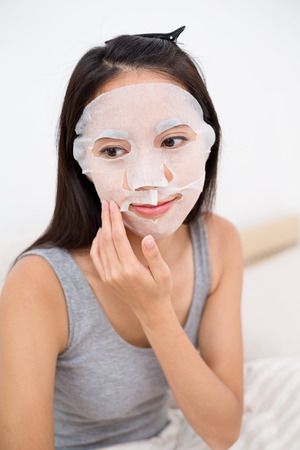 Woman use of the paper mask on bedの写真素材
