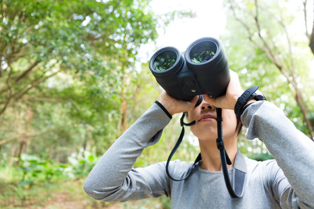 Young woman use of the binoculars and looking upの写真素材