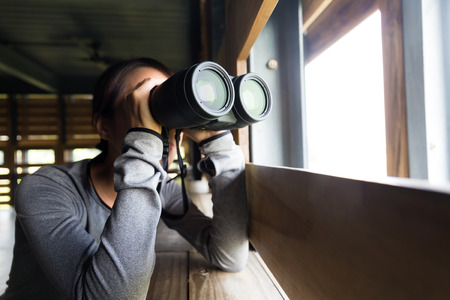 Young woman use of the binocular in wooden houseの写真素材