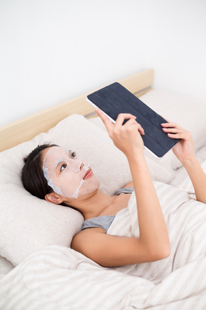 Asian Woman use of the tablet pc and use of the paper maskの写真素材
