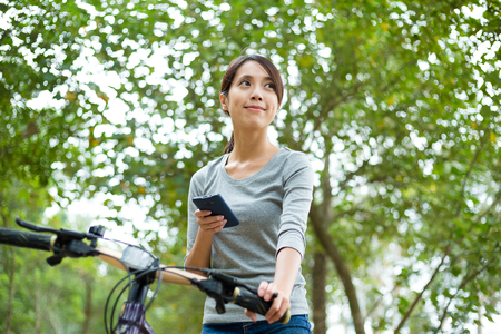 Woman use of the smart phone and riding a bikeの写真素材