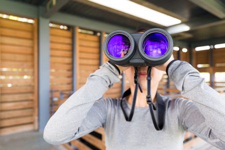 Young woman use of the binoculars at wooden houseの写真素材