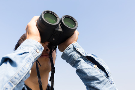 Man looking though binoculars with clear blue skyの写真素材