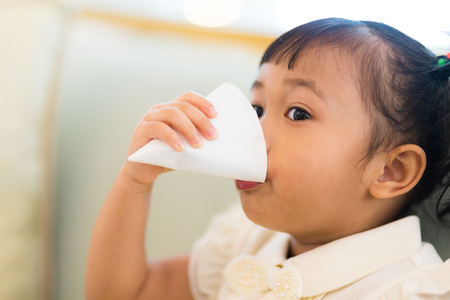 Little girl feel thirsty and drinking a paper cup of waterの写真素材