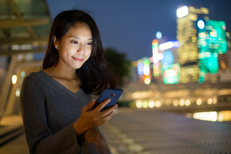 Woman look at mobile phone at nightの写真素材