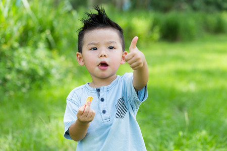 Little boy having his snack with thumb up gestureの写真素材