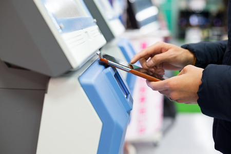 Woman using cellphone for paying on machine