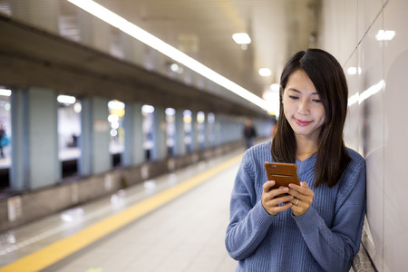 Woman use of cellphone in underground metro stationの写真素材