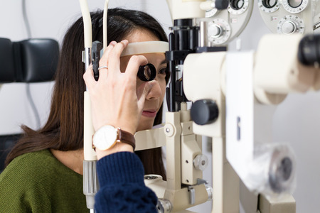Woman checking vision with tonometer at eye clinicの写真素材
