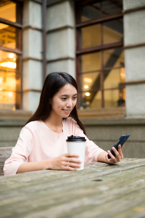 Woman read on mobile phone with her coffeeの写真素材