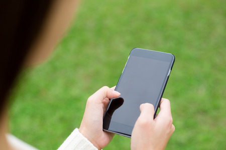 Woman use of cellphone over green grassの写真素材