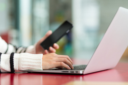 Woman working on laptop computer and cellphoneの写真素材