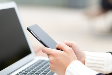 Woman touch on cellphone and notebook computerの写真素材