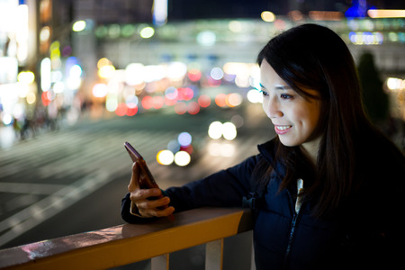 Woman look at her cellphone at nightの写真素材