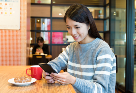 Woman use of mobile phone in coffee shopの写真素材