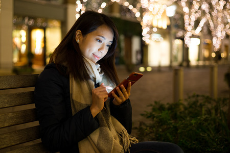 Woman using cellphone at nightの写真素材