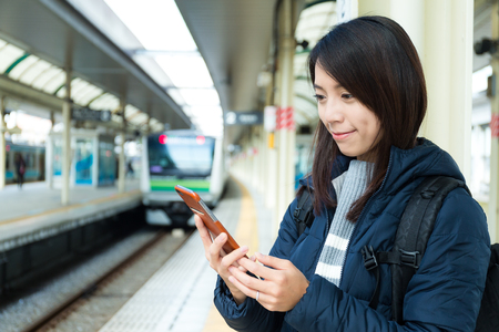 Woman use of mobile phone in trains stationの写真素材