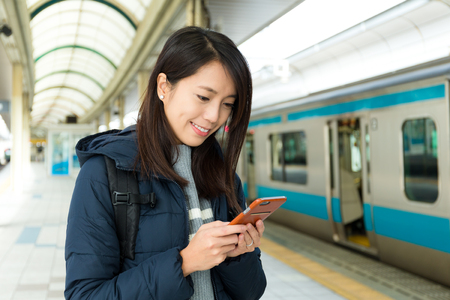 Woman use of cellphone in trains stationの写真素材