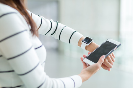 Woman connecting smartwatch and cellphoneの写真素材
