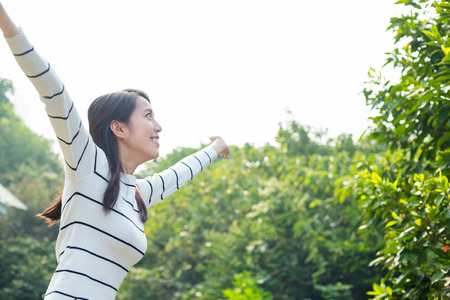 Woman raising her arms up at green parkの写真素材