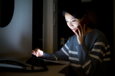 Woman use of tablet and talk to cellphone at nightの写真素材