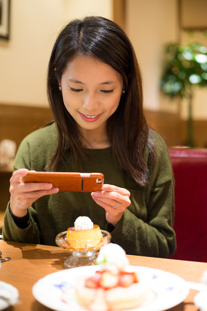 Woman use of cellphone to take photo on her dessertの写真素材