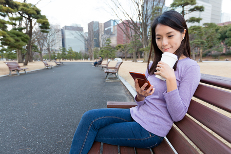Woman drinking coffee and use of mobile phoneの写真素材