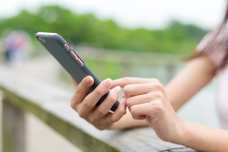 Woman touch on cellphone in parkの写真素材