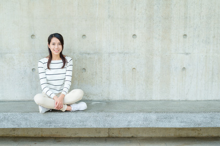 Young woman against concrete wallの写真素材