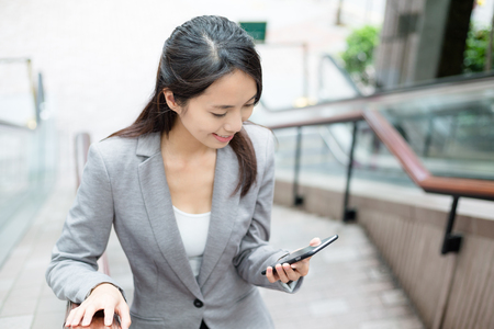Business woman walking up stairs and look at cellphoneの写真素材