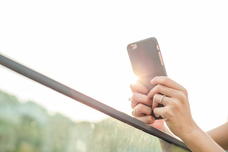 Woman using cellphone with sun flareの写真素材