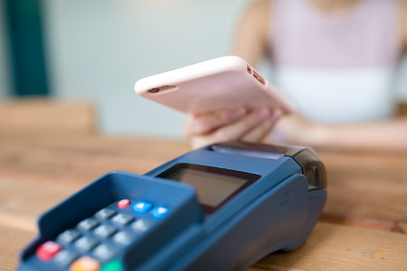 Woman using mobile phone to pay on pos terminalの写真素材