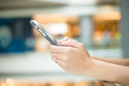 Woman using smartphone in shopping centerの素材 [FY31057605619]