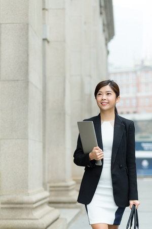 Confident Business woman hold with laptop computer and walking on streetの写真素材