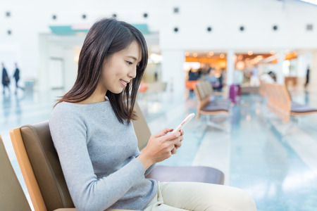 Woman using mobile phone at airportの写真素材