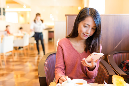 Woman using cellphone in coffee shopの写真素材