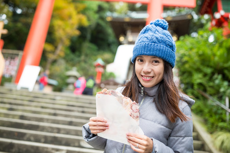 Woman visit kamakura city and eating famous crispy squid snackの写真素材