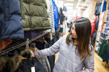 Woman choosing jacket in boutiqueの写真素材