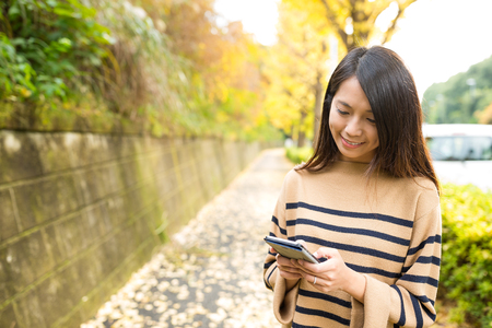 Woman using mobile phone at outdoor parkの写真素材