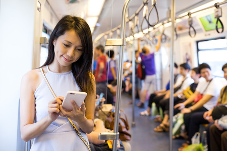 Woman using cellphone inside train compartmentの写真素材