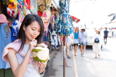 Woman drinking of coconut in weekend marketの写真素材