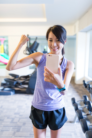 Woman showing muscle and taking selfie infront of mirrorの写真素材