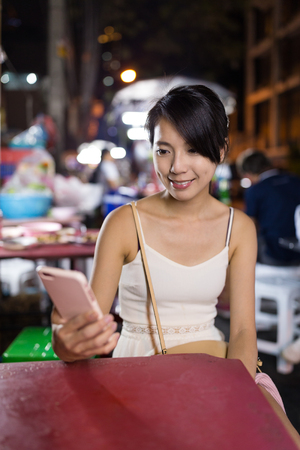 Woman use of mobile phone at outdoor night marketの写真素材