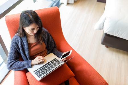 Woman working on cellphone and laptop computerの写真素材