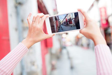 Woman taking photo on cellphone in Macauの写真素材