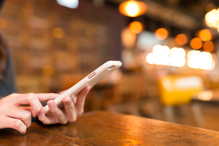 Woman sending sms on cellphone in coffee shopの写真素材