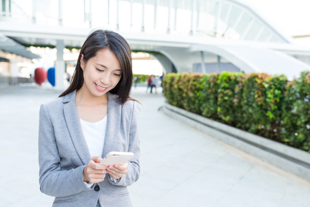 Businesswoman working on mobile phone at outdoorの写真素材