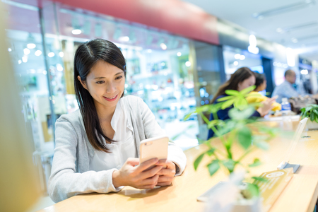 Woman use of mobile phone at coffee shopの写真素材
