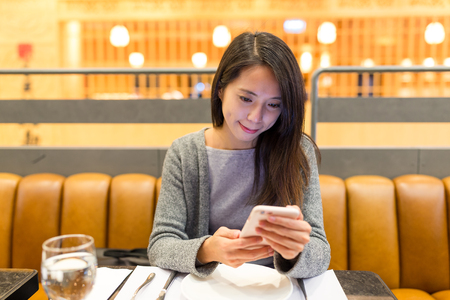 Woman use of mobile phone in restaurantの写真素材